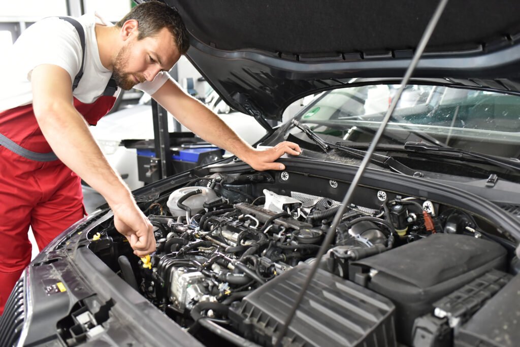 Car mechanic checks engine oil level in workshop // Kundendienst